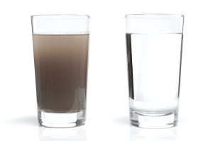 Full glass of tap water obscured by small particles. Concept for unhealthy water supply for people in developing countries.