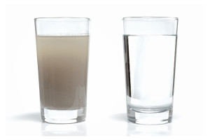 Full glass of tap water obscured by small particles. Concept for unhealthy water supply for people in developing countries.
